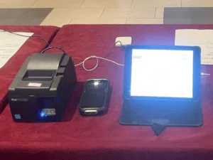 POS system with printer and tablet on red tablecloth.