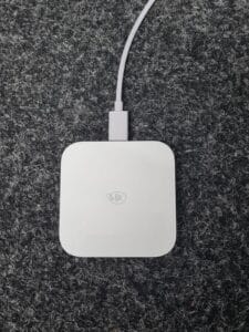 White wireless charging pad on textured grey background.