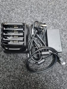 Multi-bay battery charger with cables on carpet.