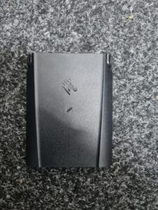 Black external hard drive on textured grey carpet.