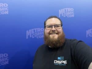 Man smiling at Metro Comic Con with blue backdrop