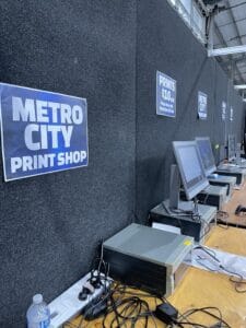 Metro City print shop booth with computers and banners