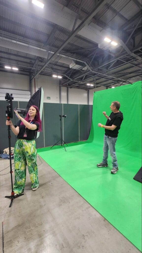 Two people setting up equipment on green screen studio