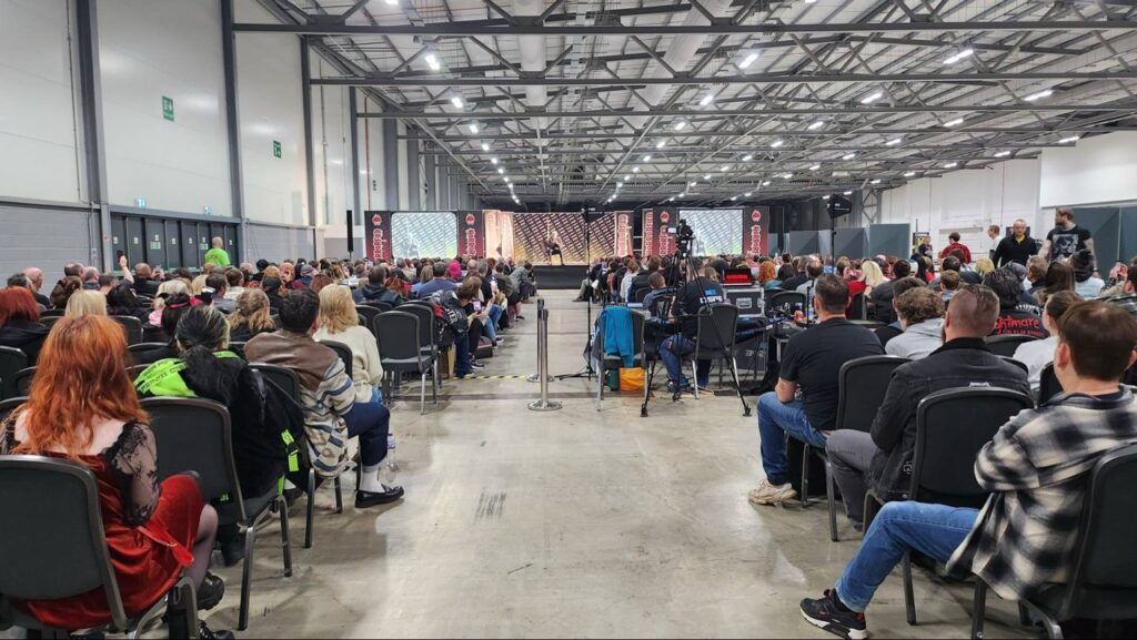 Crowded event hall with people watching a presentation