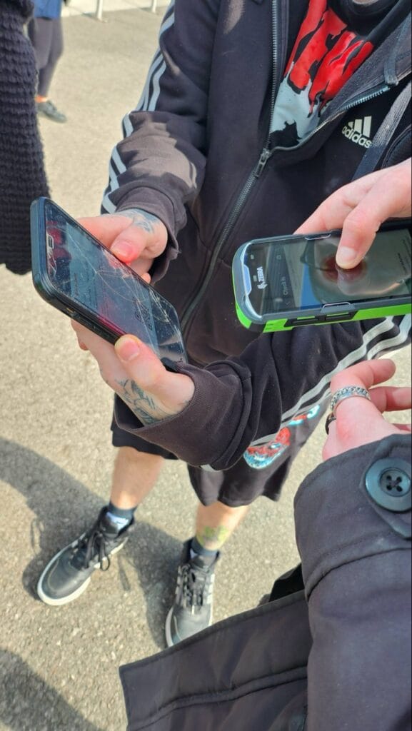 Two people exchanging mobile phones outdoors