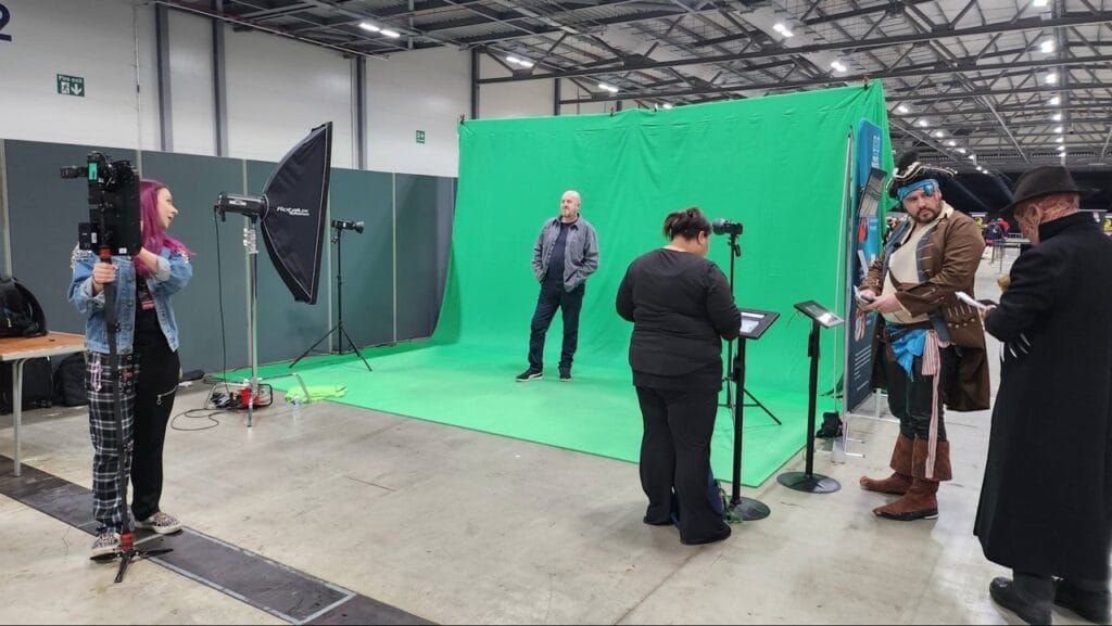 Film crew working on green screen setup at event.