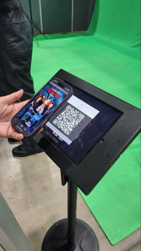 Mobile showing QR code on stand with green screen background
