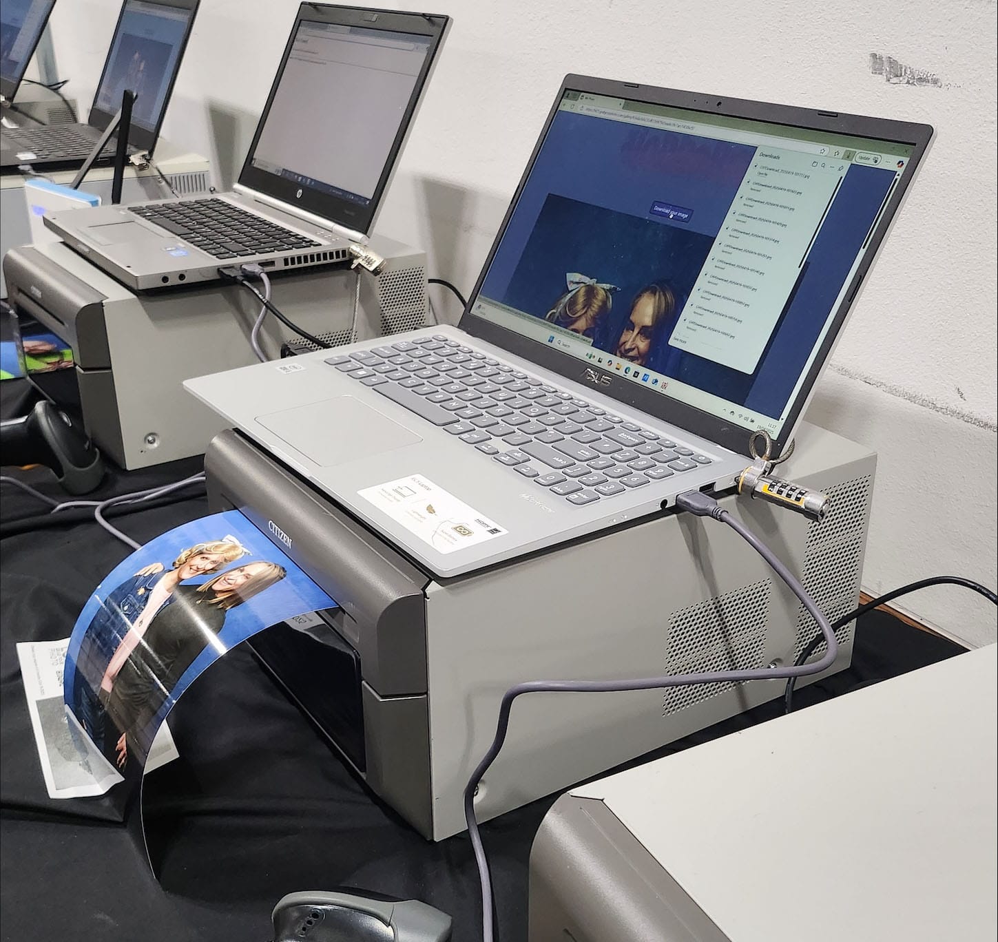 Laptops and printers processing printed photos.