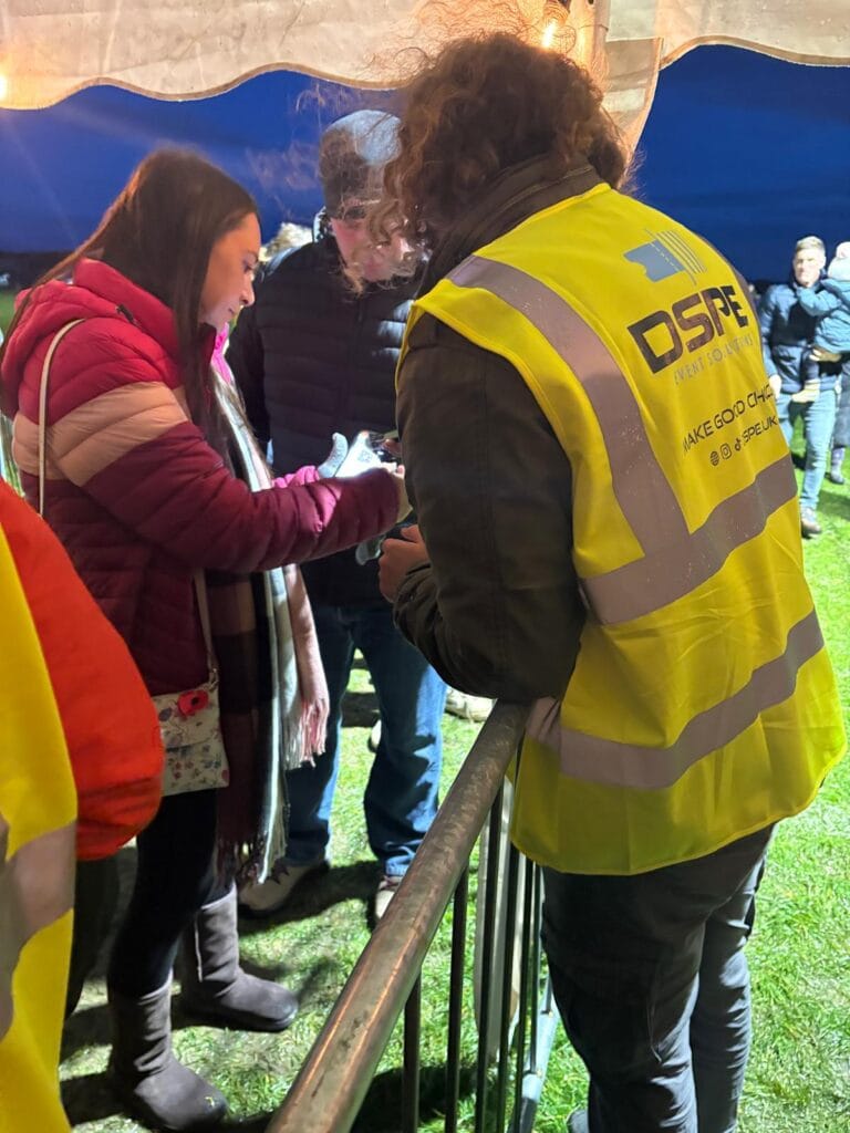 Event staff checking tickets under marquee at night